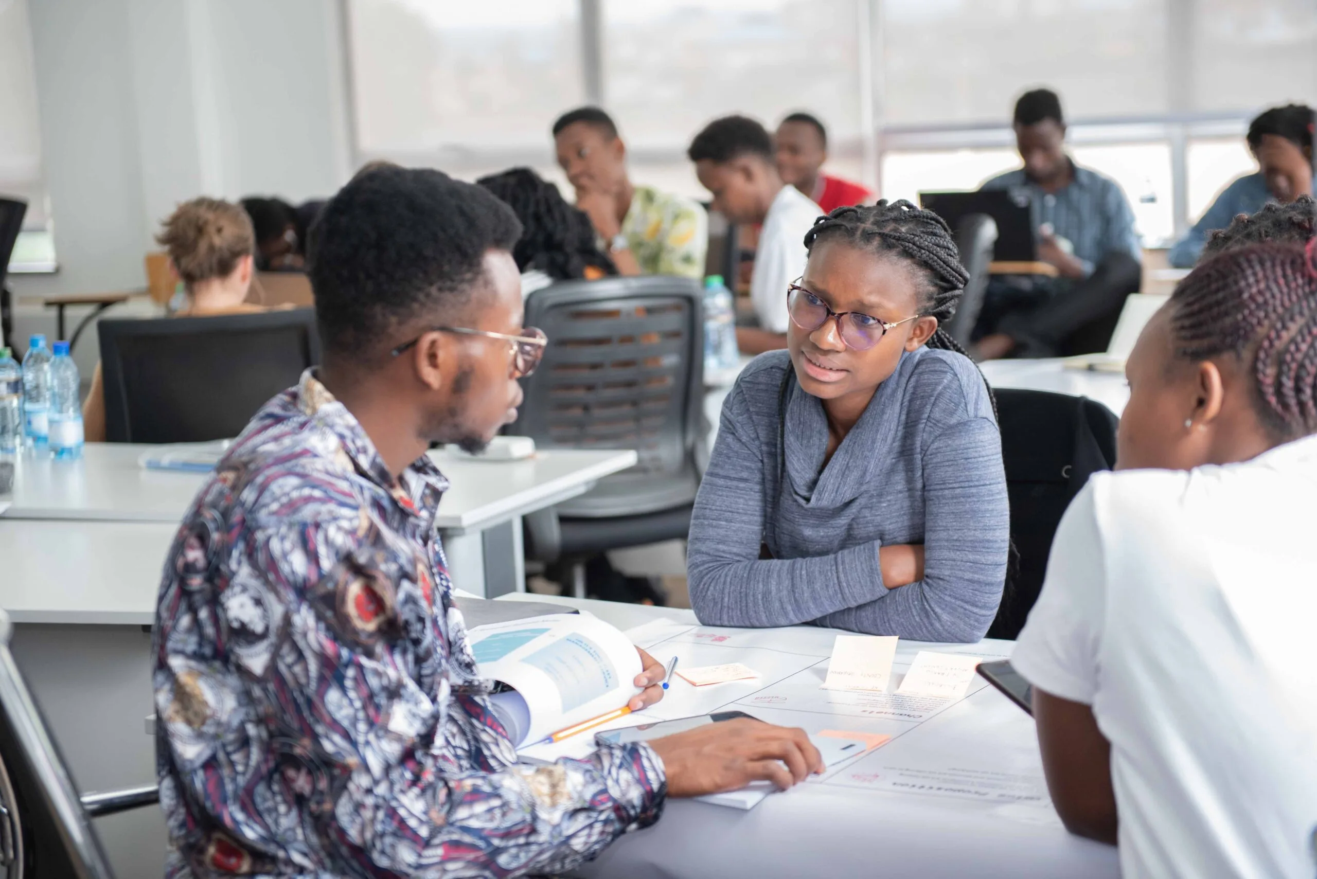 Young entrepreneurs discussing documents around a table during a workshop in Kenya, Thousand Young Entrepreneurs 2024