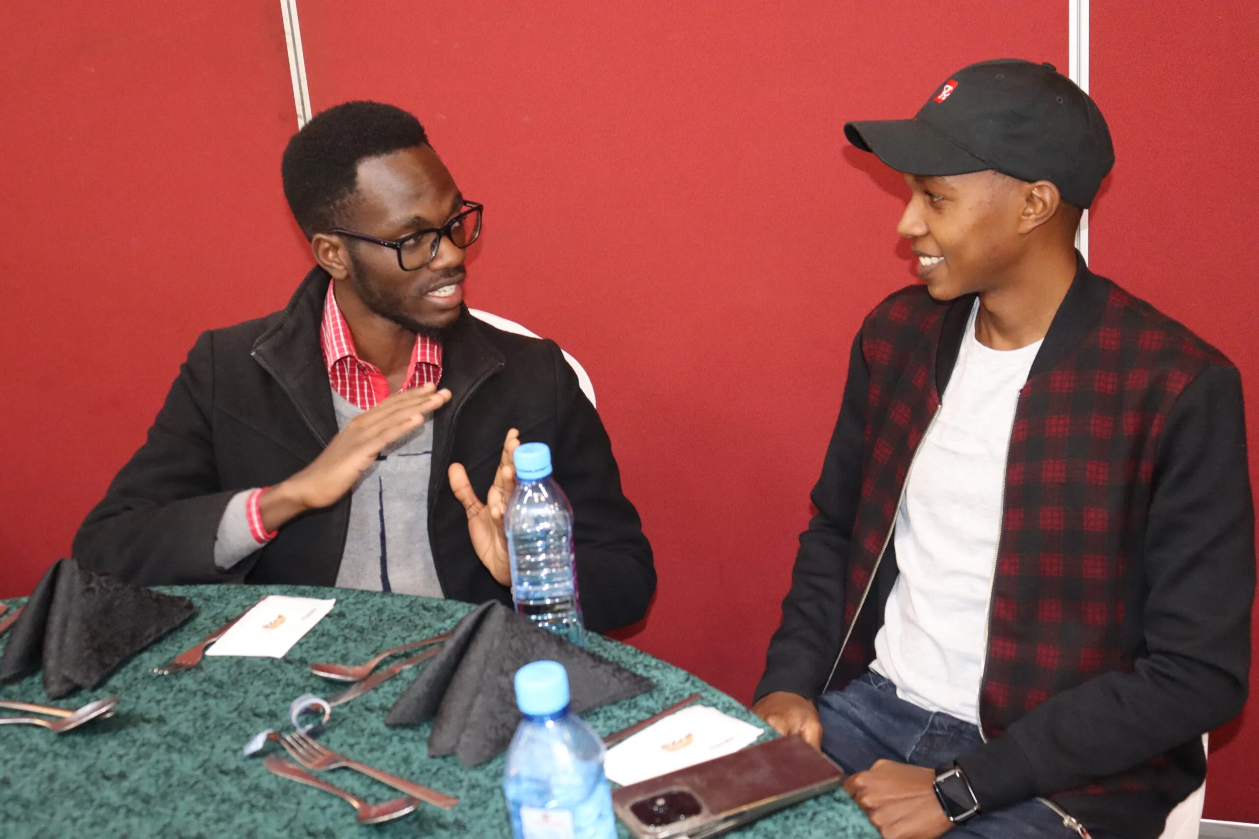 Two young entrepreneurs in conversation at a table during an event in Kenya, Thousand Young Entrepreneurs 2024