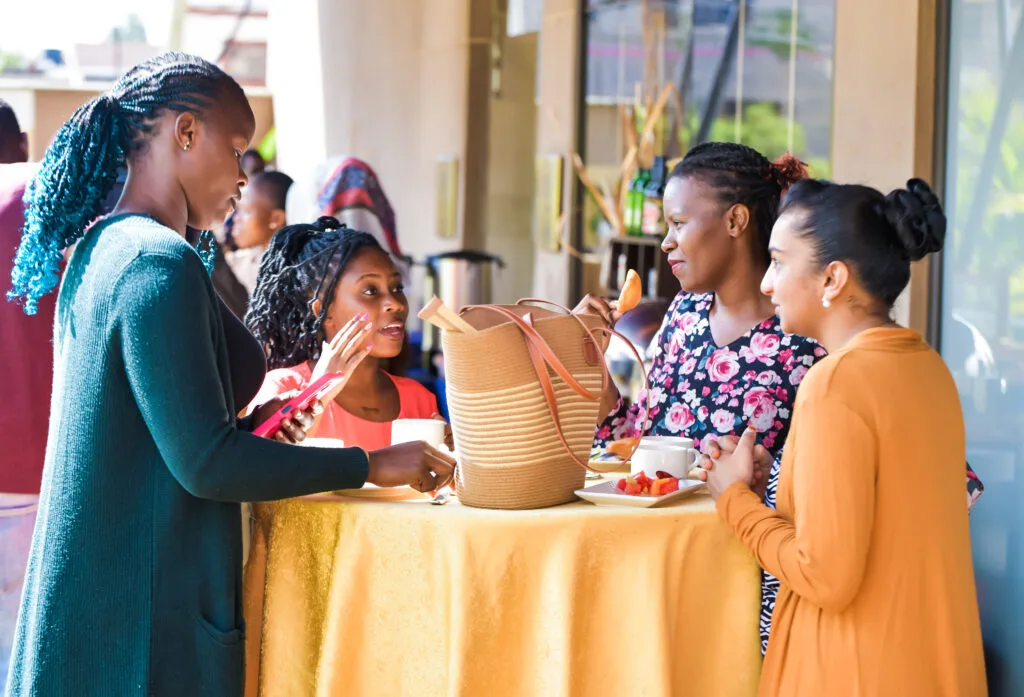 Four young entrepreneurs talking around a table with a woven basket during a networking event in Kenya, Thousand Young Entrepreneurs 2025