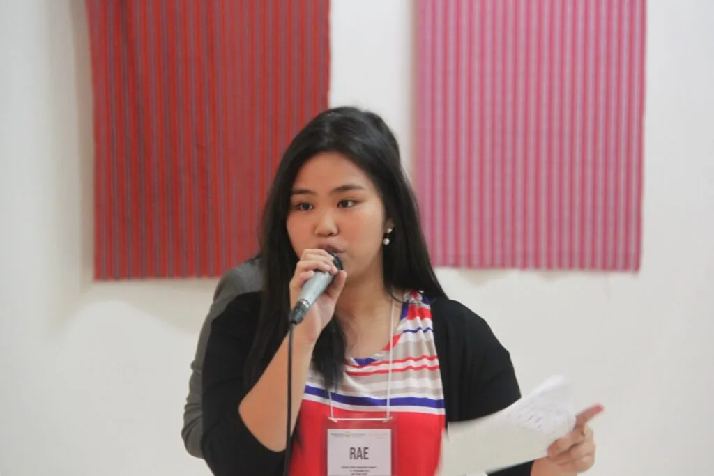 Rae, an Aiducation alumna in the Philippines, speaking into a microphone while holding her notes