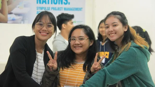Three Aiducation participants in the Philippines smiling and making peace signs at a an Academy